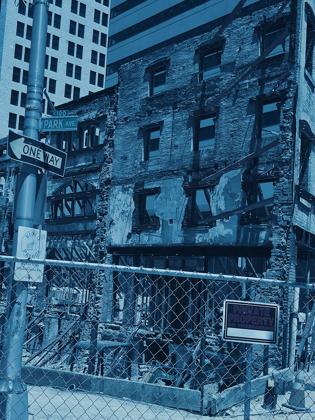A Baltimore rowhouse block under repair behind construction fencing, rendered in deep blue