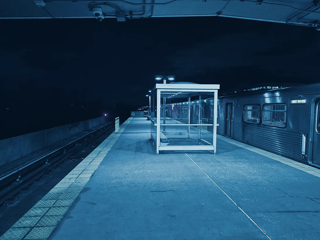 A Baltimore transit platform at night, rendered in deep blue